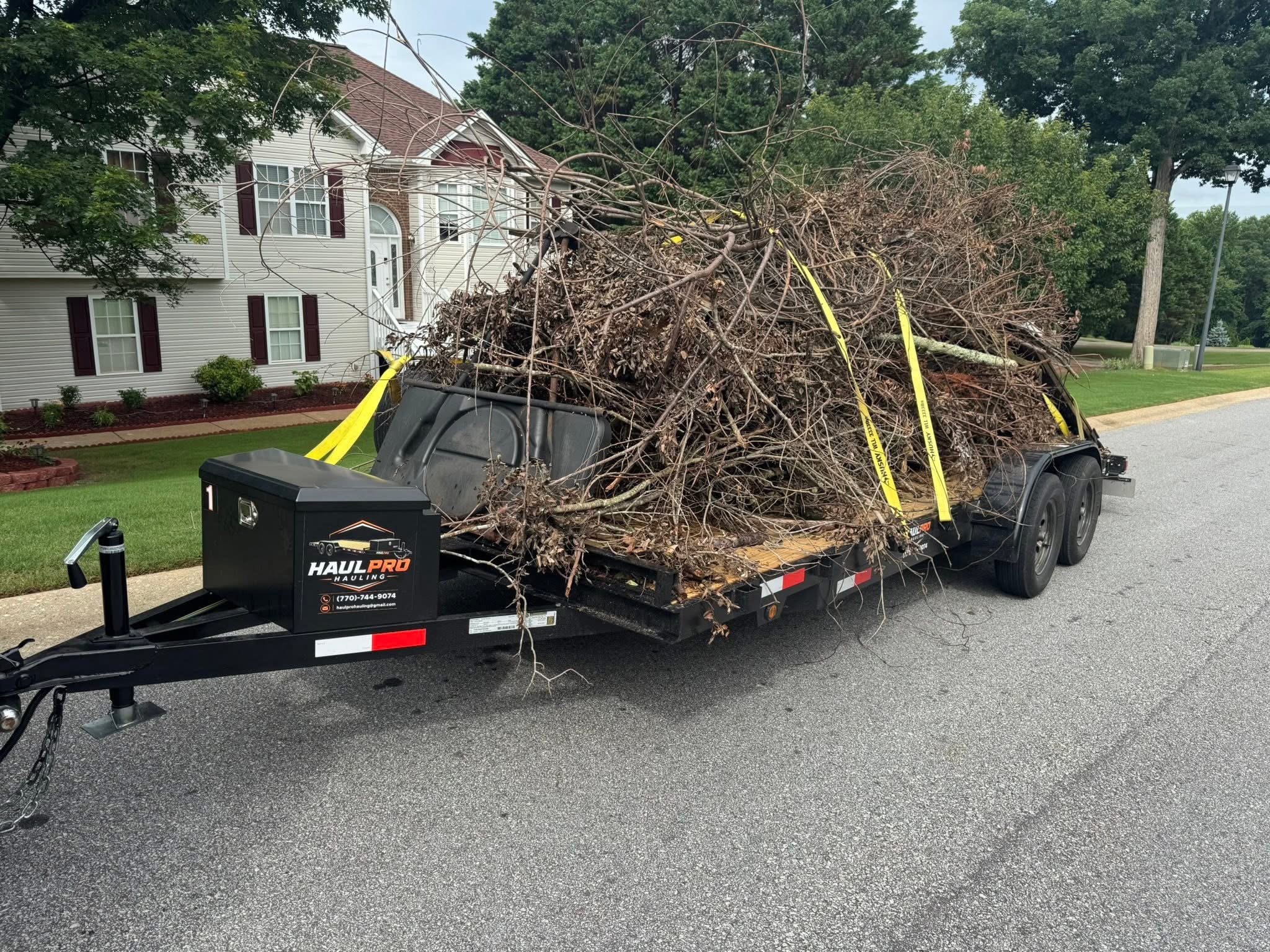 Haul Pro Hauling trailer piled high with tree branches and yard brush for removal